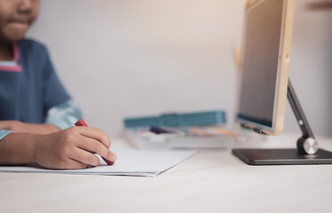 Young kid girl studying at home using a tablet , education concept.