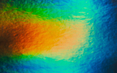 Bright multicolored glare on paper textured cardboard. Soft rainbow light. Abstract colorful background.