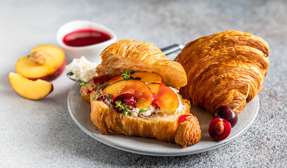 Croissant with nectarine, cherry and ricotta cheese, gray stone background. Tasty breakfast.