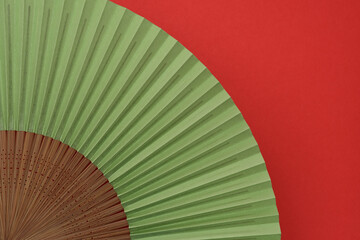 Japanese folding fan on red background.