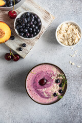 Smoothie bowl with blueberry, almond slices with fresh berries and fruit on wooden cutting board. Top view.