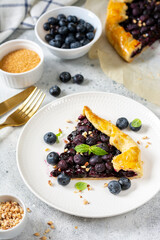 A piece of homemade galette with blueberries in a white plate on a culinary background close-up. Delicious sweet pastries