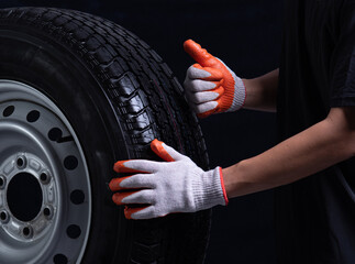 Auto mechanic checking a car tire on a black background,showing thumb up
