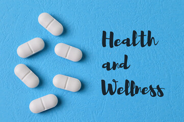 Pill capsules on blue background with text HEALTH and WELLNESS