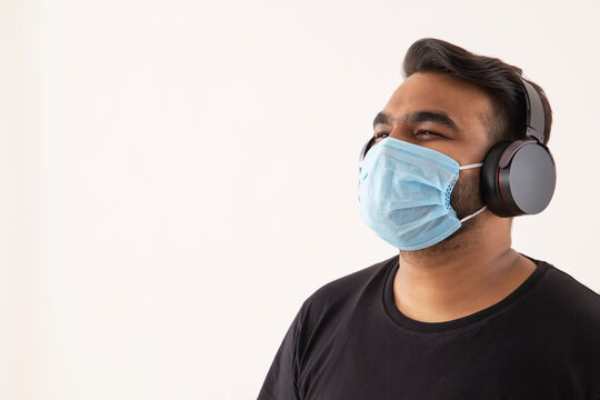 Portrait of a young man with headphones and mask on his face.