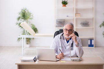 Fototapeta premium Old male doctor working in the clinic