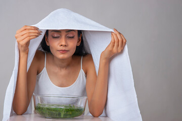 A young woman taking steam of organic leaves for skin care. - obrazy, fototapety, plakaty
