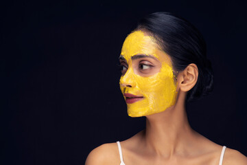A young woman's face with home made face mask applied for skin care looking sideways.
