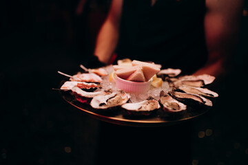Close-up of hands holding a plate of oysters