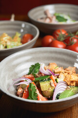 Salad with beef, onion and cilantro in sweet and sour sauce. Served in a bowl over rustic wooden background.