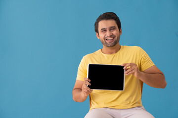 A young man laughing while showing a tablet phone in his hand.