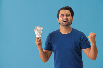 A happy, young man holding Indian currency notes in his hand.