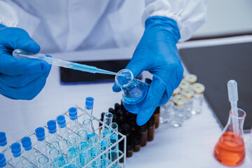 Fototapeta premium medical or scientific researcher researching and experimenting Multi-colored solution, vial and microscope In the laboratory or in the laboratory by wearing blue gloves and white clothing completely.