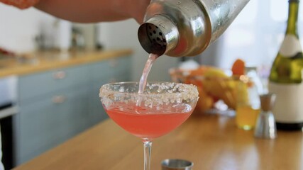 drinks and people concept - young woman with shaker pouring cocktail to glass and decorating it with thyme at home kitchen