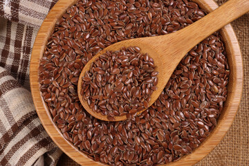 Flex seed flaxseed in wooden bowl spoon on jute fabric cloths top view