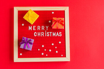 merry christmas festive background with red letter board and small gift boxes and copy space