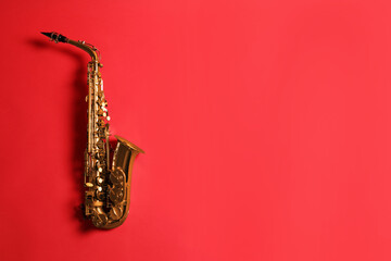 Beautiful saxophone on red background, top view. Space for text - obrazy, fototapety, plakaty