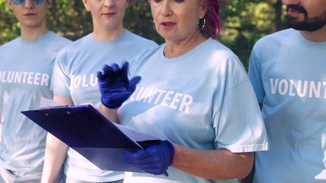 Group of volunteers ready to perform task, senior woman giving instructions