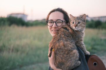 Smiling girl walking with domestic cat in the town. - 448714677