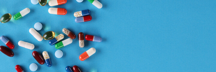 Multi-colored medical pills lie on blue background