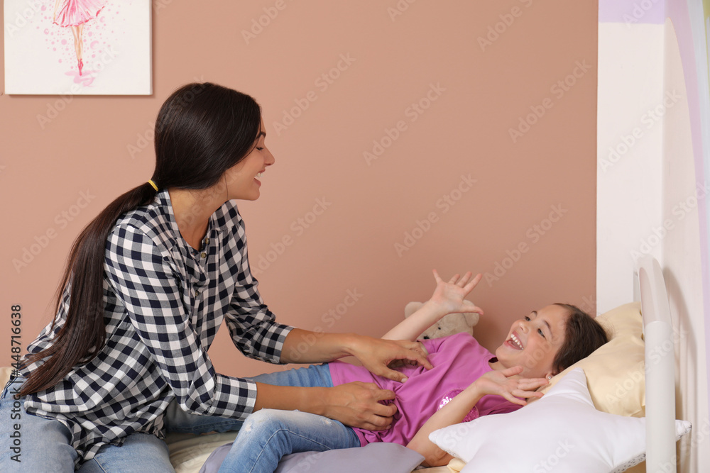 Wall mural Happy single mother playing with her daughter in bedroom