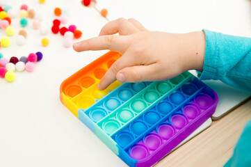 Child plays with sensory fidget toy Pop-it. Instrument for fine motoric skils, tool to start...