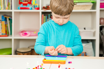 Child plays with sensory fidget toy Pop-it. Instrument for fine motoric skils, tool to start...