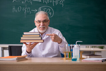 Old male chemist teacher in the classroom