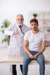 Fototapeta premium Young male patient visiting old male doctor