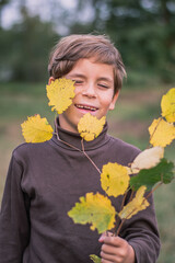 Happy boy with a light of yellow leaves