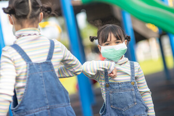 new normal lifestyle, social distancing concept. happy kids wearing face masks having fun on at playground protect coronavirus covid-19,