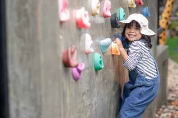 Asian little girl climbing a rock wall - Powered by Adobe