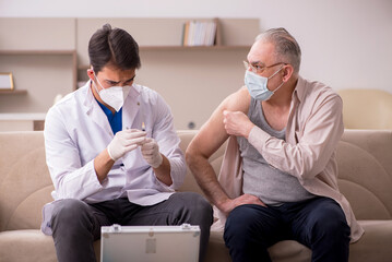 Young male doctor visiting old patient in vaccination concept