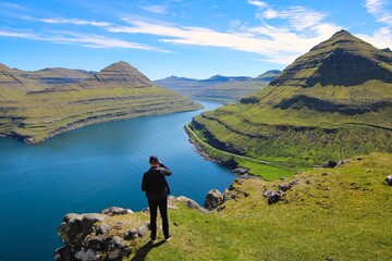 Man standing on a mountain, enjoying the great scenery of Faroe Islands - obrazy, fototapety, plakaty