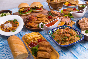 Wooden table full of delicious grilled bbq and fried food. Meat and vegetables. Summer picnic background. Delicious dinner.