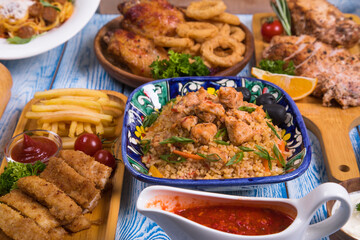 Wooden table full of delicious grilled bbq and fried food. Meat and vegetables. Summer picnic background. Delicious dinner.