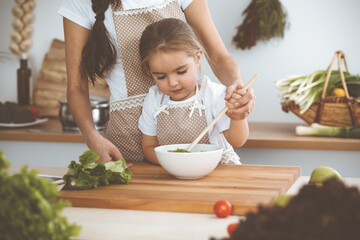 Happy woman and her daughter making healthy vegan salad and snacks for family feasting. Christmas, New year, Thanksgiving, Anniversary, Mothers Day. Healthy meal cooking concept