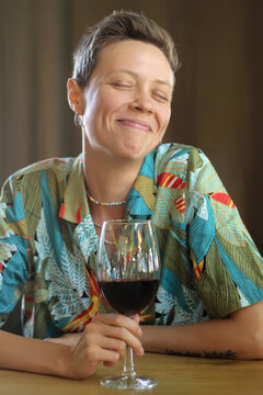 A lisbian girl sits in a restaurant with a glass of wine in her hand. 