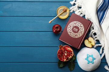 Flat lay composition with Rosh Hashanah holiday attributes on blue wooden table. Torah book with...