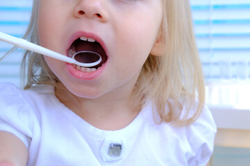 closeup female hands, dentist, doctor examines oral cavity of small patient, blonde girl 2 years...