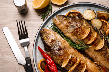 Tasty homemade roasted perches served on wooden table, flat lay. River fish