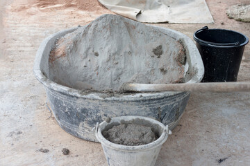 Cement and hoe in plastic bucket  for mixer in construction site.