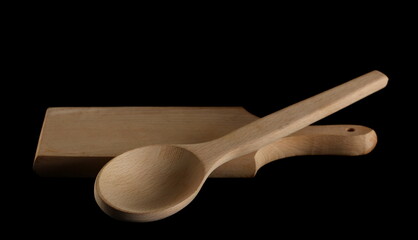 Empty wooden spoon and chopping board isolated on black background with clipping path