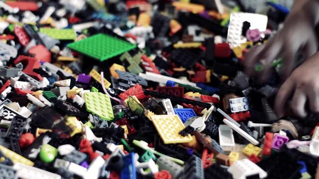 A bunch of multi-colored constructor. a child's hand is looking for a detail.