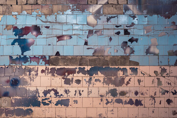 An old colorful wall with peeling ceramic tiles and peeling paint. Background