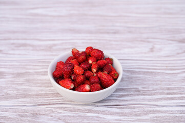 Fresh ripe strawberries in white bowl, on wooden table