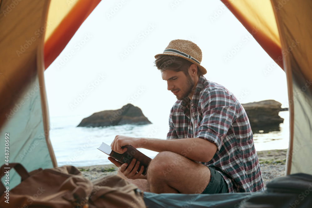 Poster european guy read book on sandy sea beach