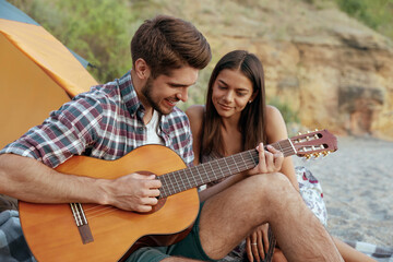 Happy guy play on guitar to beautiful smiling girl