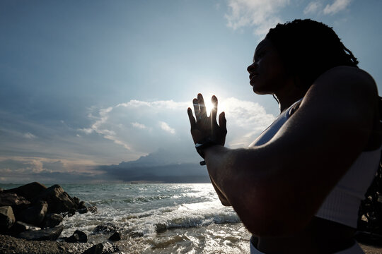 Lovely for young sportswoman doing namaste mudra when meditating in rays of setting sun