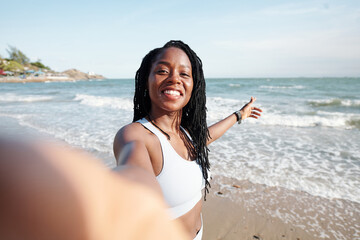Pretty young woman with dreadlocks smiling and taking selfie on beach - Powered by Adobe